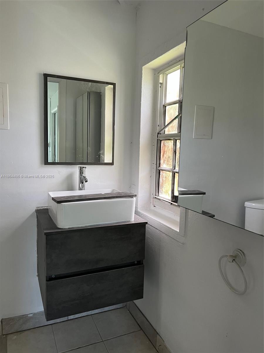 A bathroom features a floating dark vanity, a white vessel sink, and a wall mirror — 802 S 24th Ave, Hollywood FL 33020, HOLLYWOOD, FL