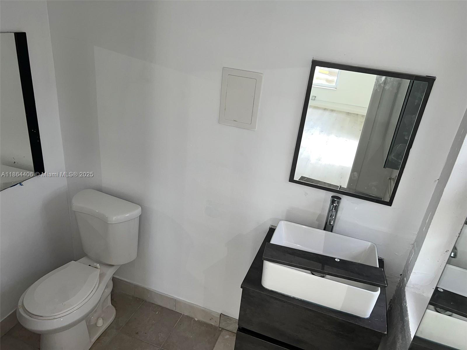 A bathroom features a white toilet, a dark vanity with a vessel sink, and mirrors — 802 S 24th Ave, Hollywood FL 33020, HOLLYWOOD, FL