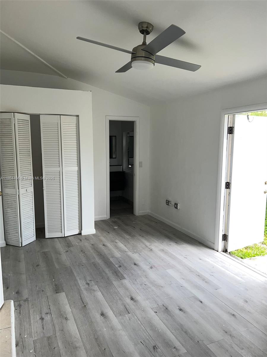 A bedroom features light wood-look flooring, a ceiling fan, white louvered closet doors, and an exit — 802 S 24th Ave, Hollywood FL 33020, HOLLYWOOD, FL