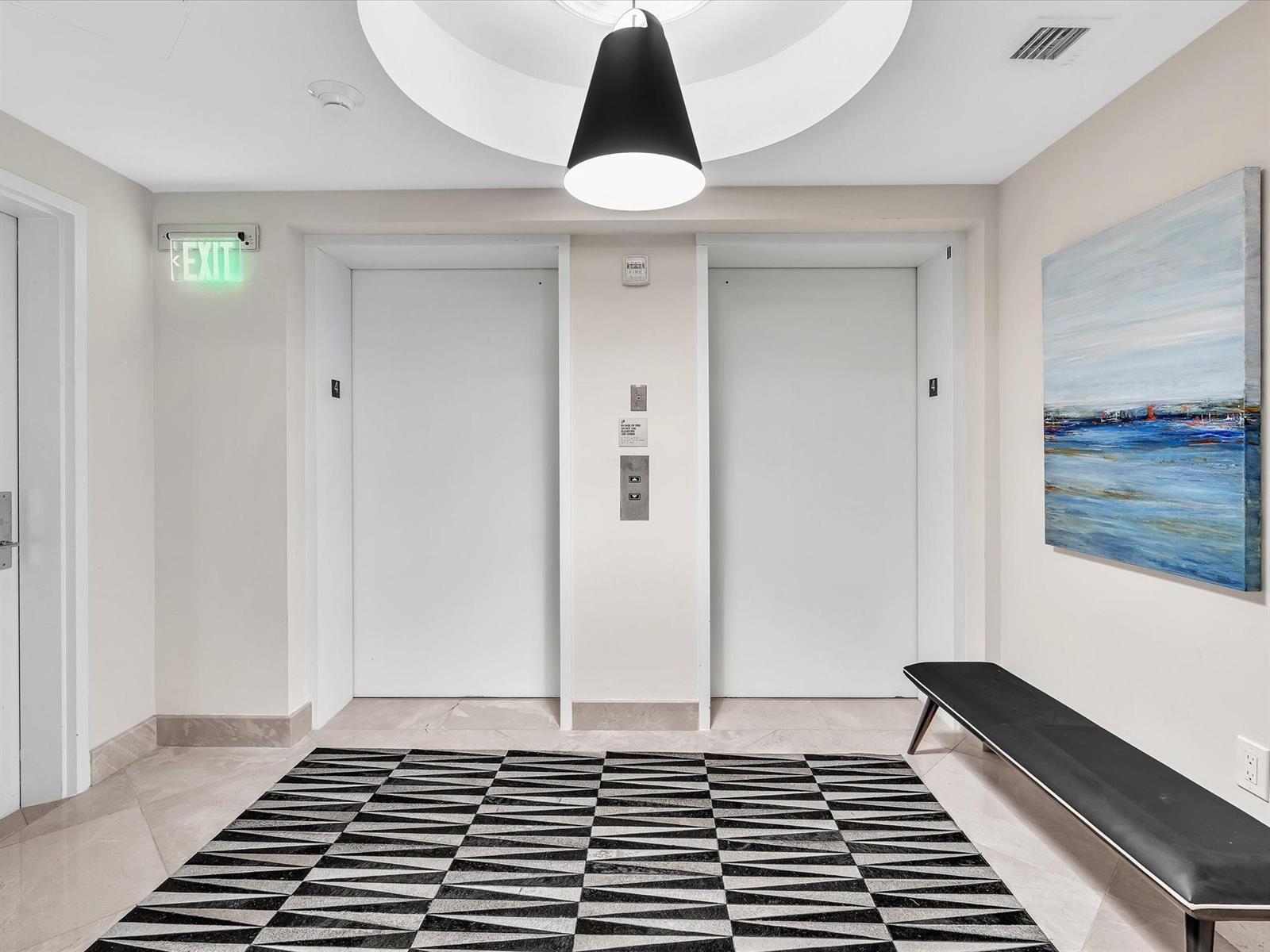 An elevator lobby features two white doors, a geometric rug, and a modern pendant light — 1600 S Ocean Boulevard, Pompano Beach FL 33062, POMPANO BEACH, FL
