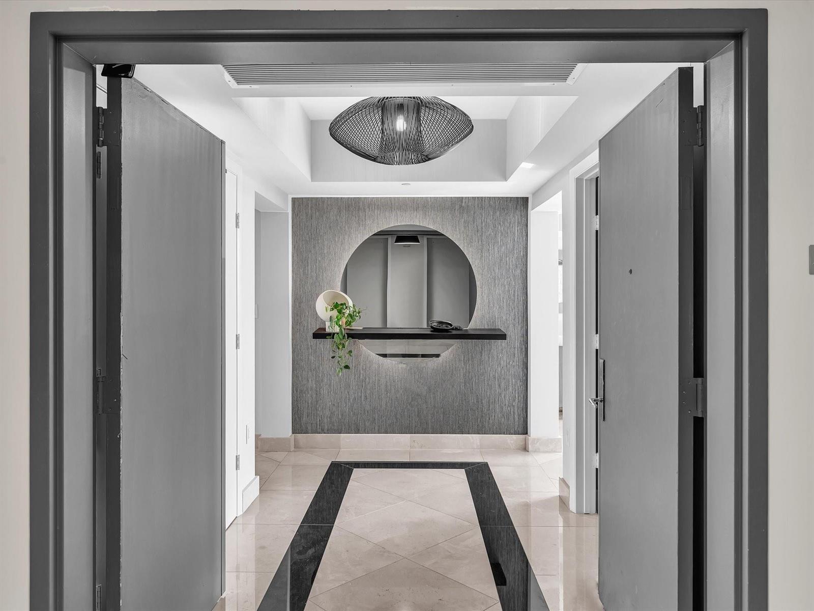 A modern entryway features a circular mirror, a floating shelf, and a unique pendant light — 1600 S Ocean Boulevard, Pompano Beach FL 33062, POMPANO BEACH, FL