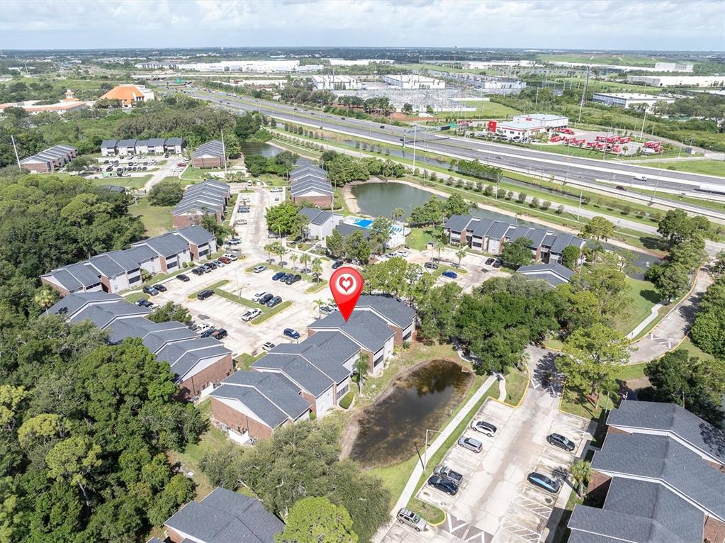 An aerial view shows a multi-building apartment complex with parking lots and a small pond — 1400 GANDY BOULEVARD N UNIT 1306, ST PETERSBURG, FL