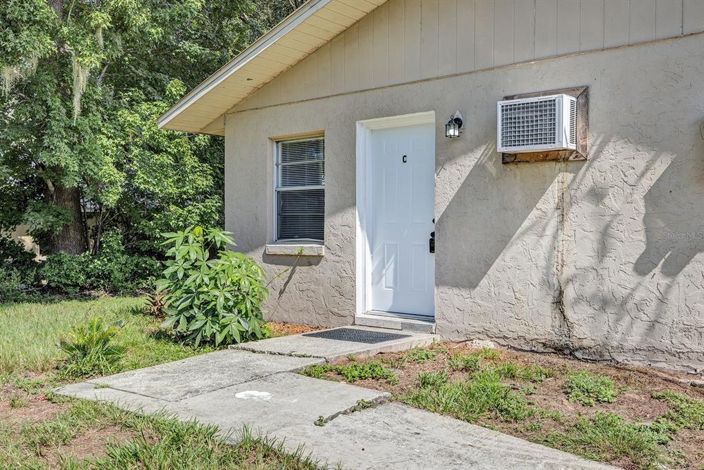 The exterior of a beige stucco building features a white door labeled C and a window — 506 NE 28TH AVENUE UNIT C, OCALA, FL