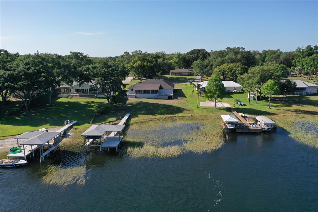 An aerial view of waterfront houses with private boat docks on a grassy lakefront lot — 10713 DENALI DRIVE, CLERMONT, FL