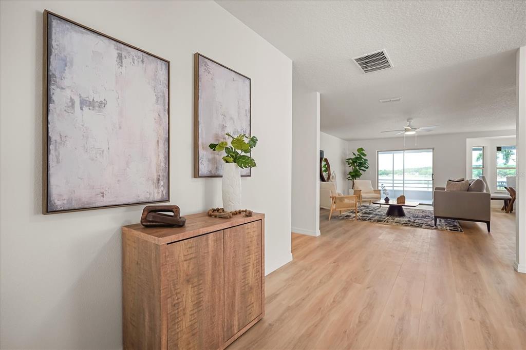 A wooden cabinet sits in a hallway leading to a living room with light flooring — 10713 DENALI DRIVE, CLERMONT, FL