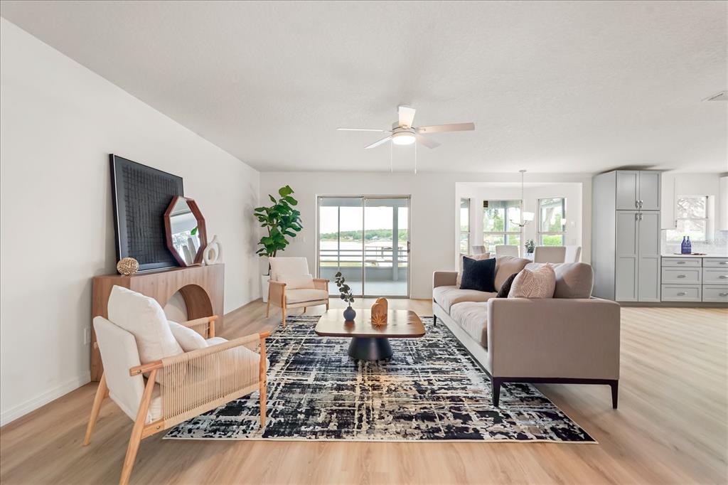 A living room with light wood flooring, a patterned rug, and a view of water — 10713 DENALI DRIVE, CLERMONT, FL