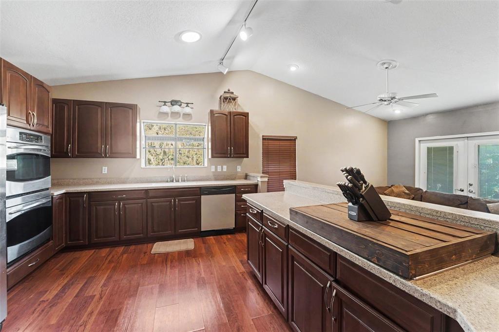 A kitchen with dark wood cabinets, stainless steel appliances, and a large central island — 5422 FOLEY SQUARE, NEW PORT RICHEY, FL