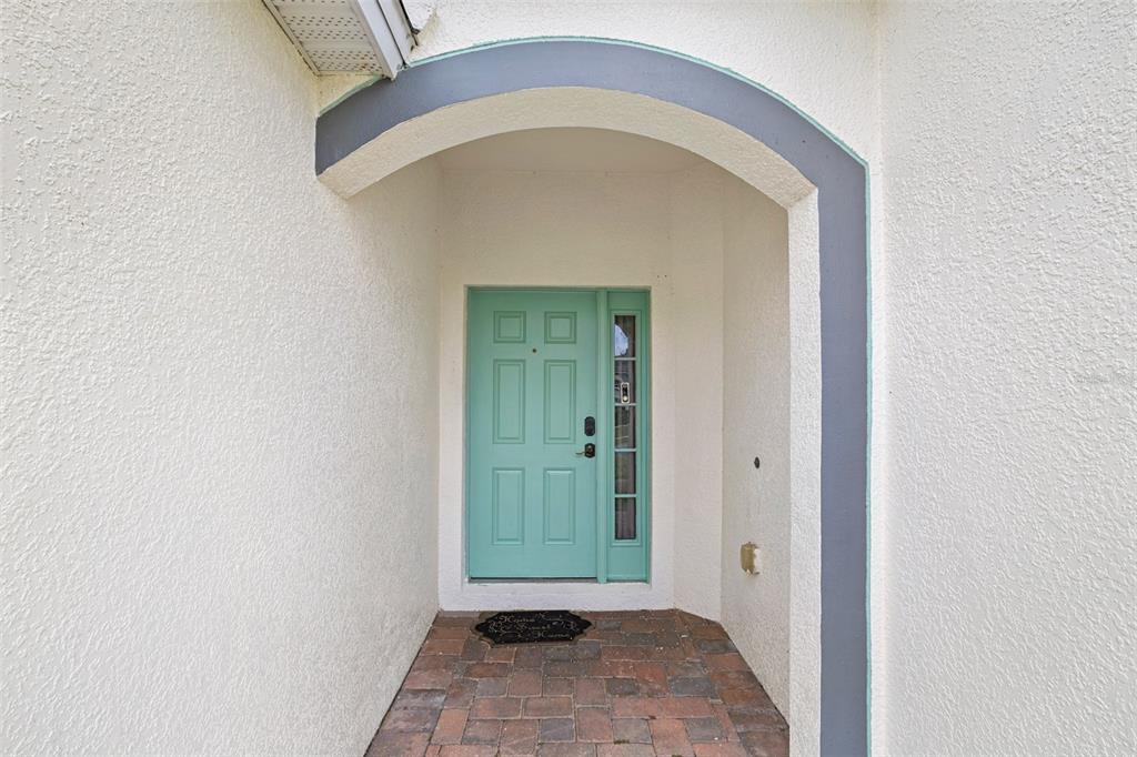 A teal front door with a sidelight sits under a gray arched entryway — 16236 DEER CHASE LOOP, ORLANDO, FL