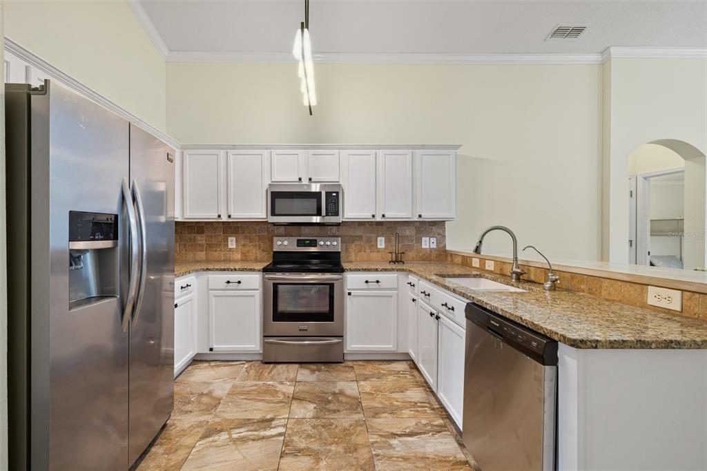 A kitchen with white cabinets, stainless steel appliances, granite countertops, and brown tile flooring — 16236 DEER CHASE LOOP, ORLANDO, FL