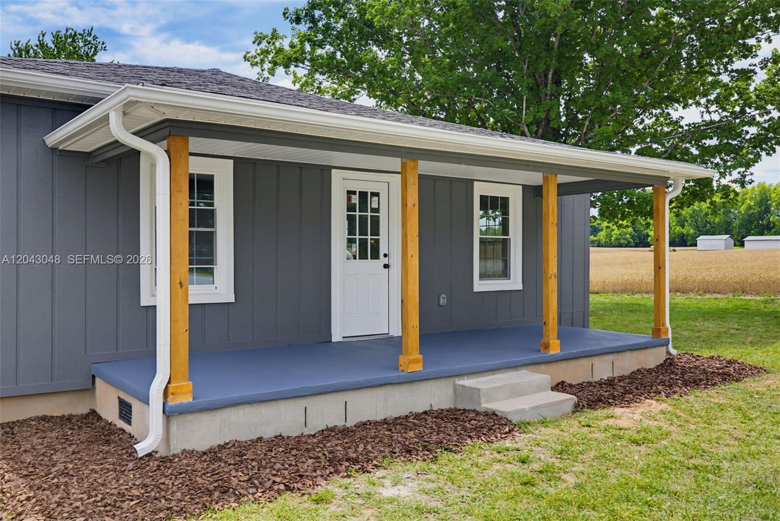 A gray house with a covered porch featuring wooden posts and a white door — 7922 Troxler Mill Road, NC 27249, NC