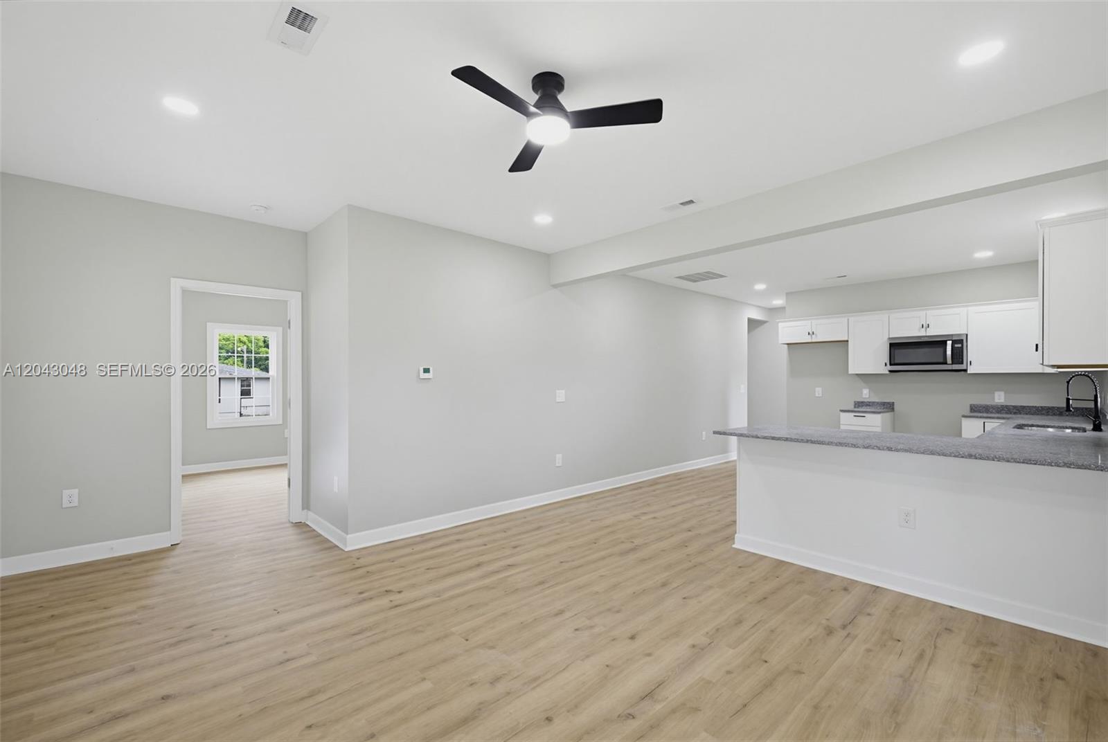 An open-concept living area features light wood-look flooring, a ceiling fan, and a kitchen — 7922 Troxler Mill Road, NC 27249, NC