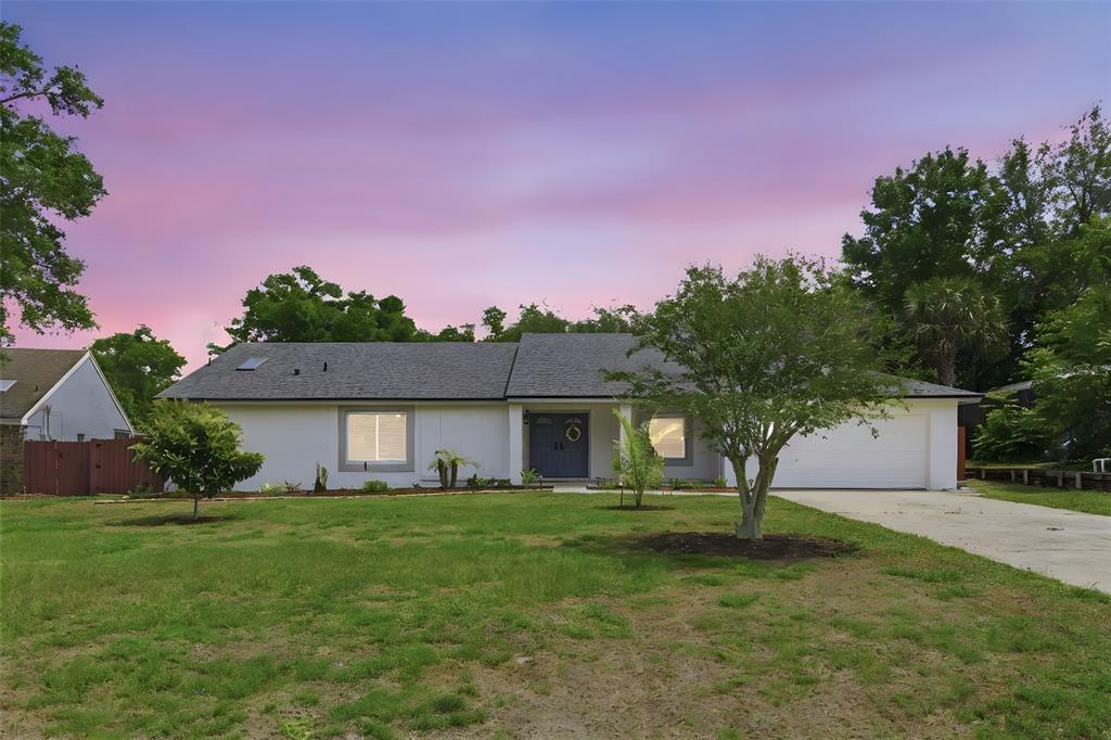 A single-story white house with a gray roof, a two-car garage, and a front lawn — 7432 SPARKLING LAKE RD, ORLANDO, FL