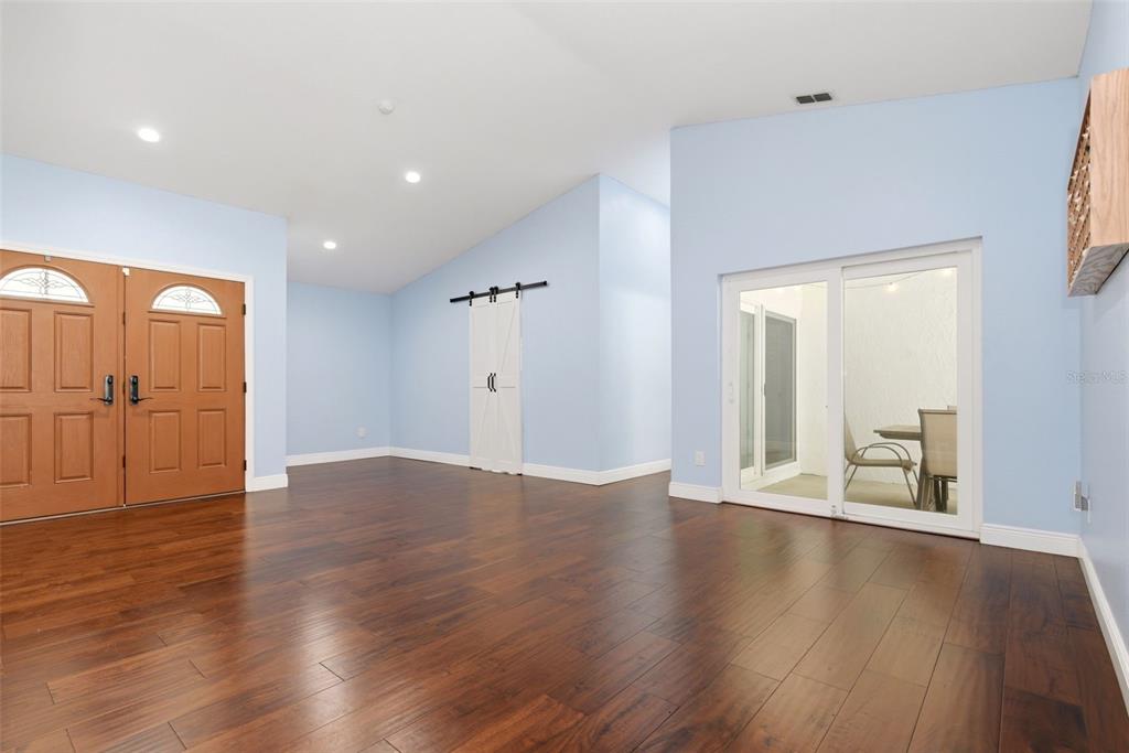 A room with light blue walls, dark wood flooring, double entry doors, and sliding glass doors — 7432 SPARKLING LAKE RD, ORLANDO, FL