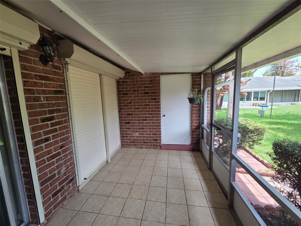 A covered, tiled patio features brick walls, roll-down shutters, and a screened-in wall — 5860 LA COSTA DRIVE, ORLANDO, FL