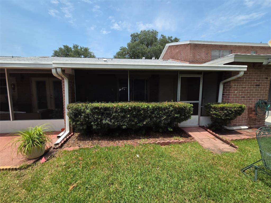 A brick house exterior features a screened-in porch with a hedge and a grassy lawn — 5860 LA COSTA DRIVE, ORLANDO, FL