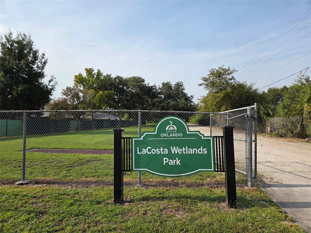 A green sign for LaCosta Wetlands Park stands in front of a chain-link fence — 5860 LA COSTA DRIVE, ORLANDO, FL