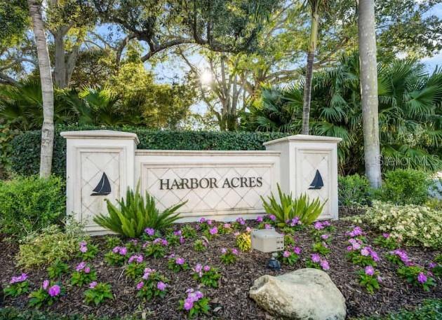 A stone monument sign for Harbor Acres sits in a garden with flowers and trees — 1387 HARBOR DRIVE, SARASOTA, FL