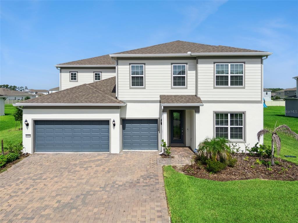 A two-story house with a three-car garage, light siding, and a paved driveway — 4330 SUNSET PRESERVE BLVD, ORLANDO, FL
