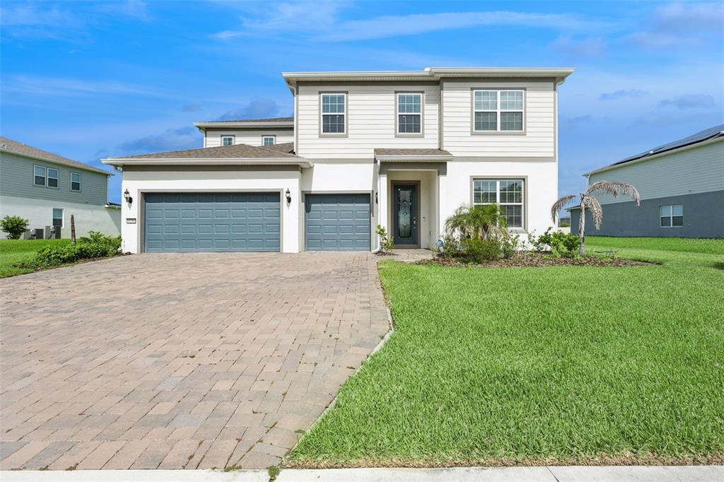 A two-story house with a paved driveway, a three-car garage, and a front lawn — 4330 SUNSET PRESERVE BLVD, ORLANDO, FL