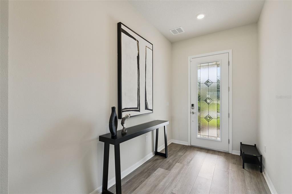 An entryway features wood-look flooring, a front door with glass, and a staircase with railings — 4330 SUNSET PRESERVE BLVD, ORLANDO, FL