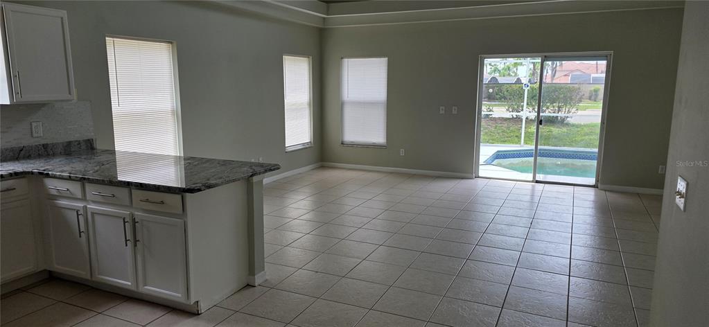 A kitchen with granite countertops overlooks a tiled living area with sliding glass doors — 103 RIGGS CIRCLE, DAVENPORT, FL