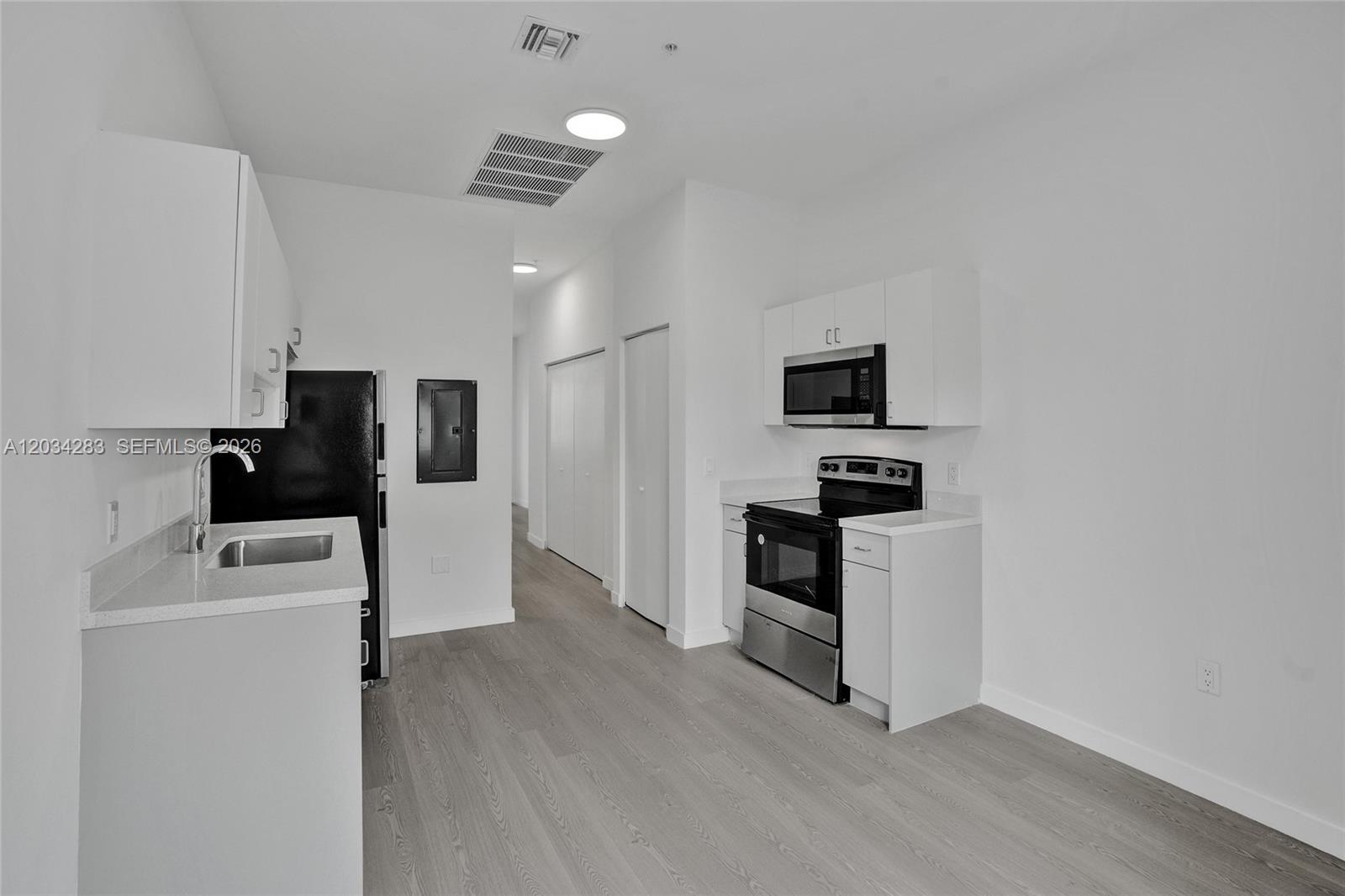 A modern kitchen features white cabinets, stainless steel appliances, and light wood-look flooring — 1567 NW 1st St # 3, Miami FL 33125, MIAMI, FL