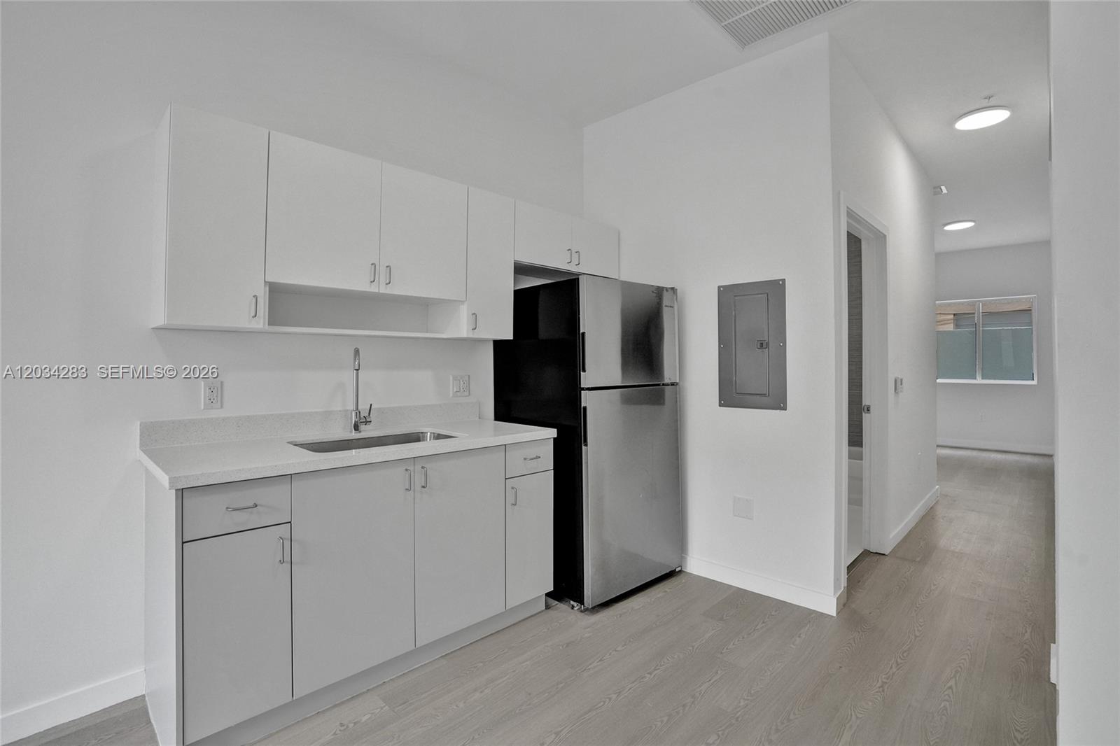 A kitchen features white cabinets, a stainless steel refrigerator, and light wood-look flooring — 1567 NW 1st St # 3, Miami FL 33125, MIAMI, FL