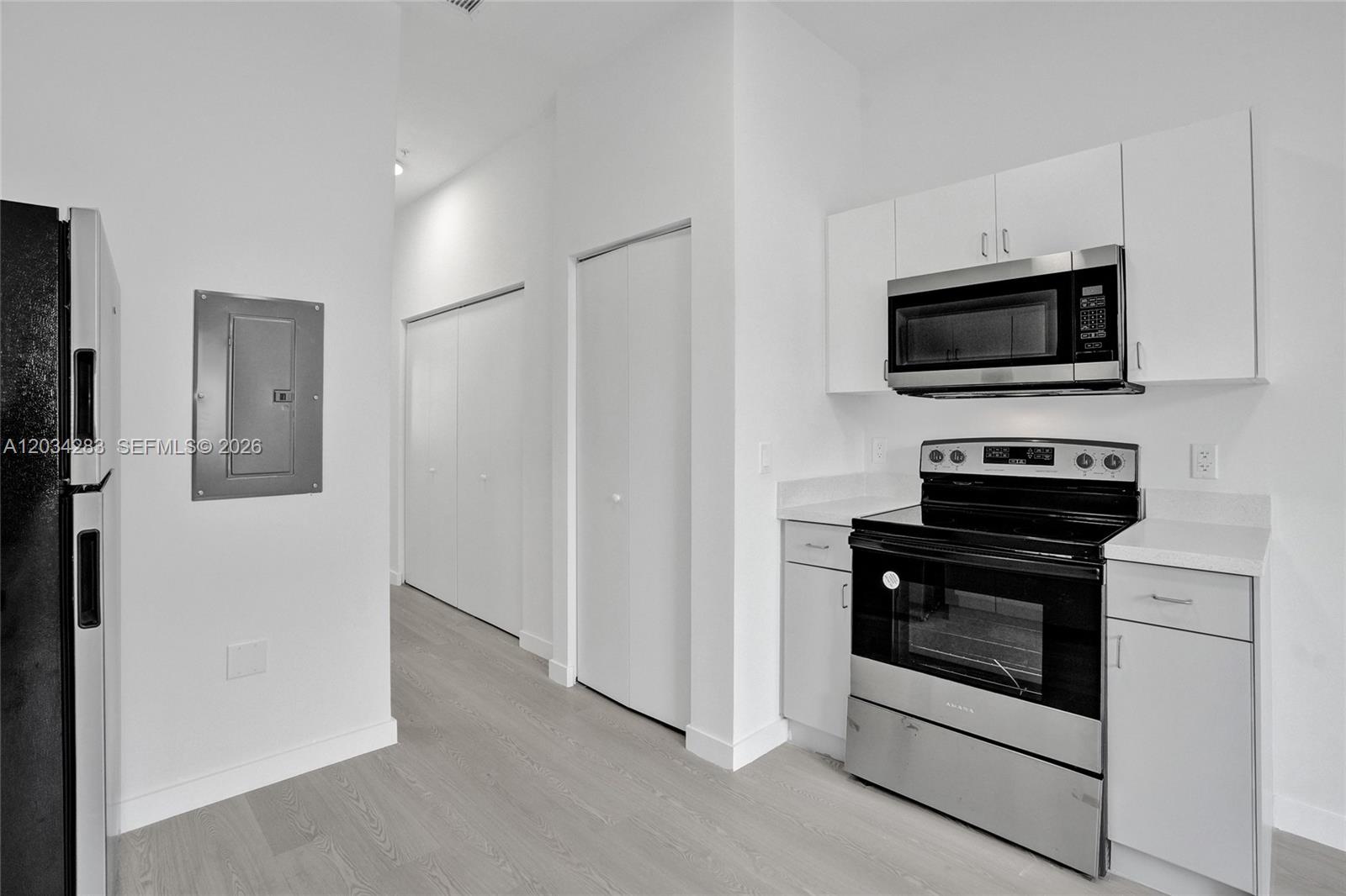 A modern kitchen features white cabinets, stainless steel appliances, and light wood-look flooring — 1567 NW 1st St # 3, Miami FL 33125, MIAMI, FL