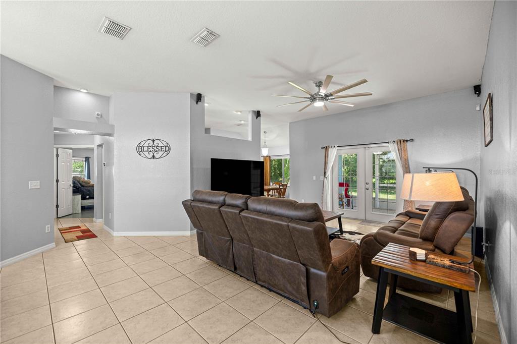 A living room features tile flooring, a brown leather sectional, and a ceiling fan — 7411 SW 128TH STREET, OCALA, FL