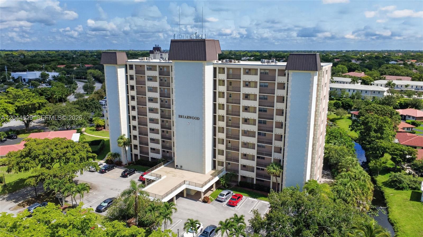 An aerial view shows a multi-story residential building named Briarwood IV with surrounding parking and landscaping — 9101 W Sample Rd # 306, Coral Springs FL 33065, CORAL SPRINGS, FL
