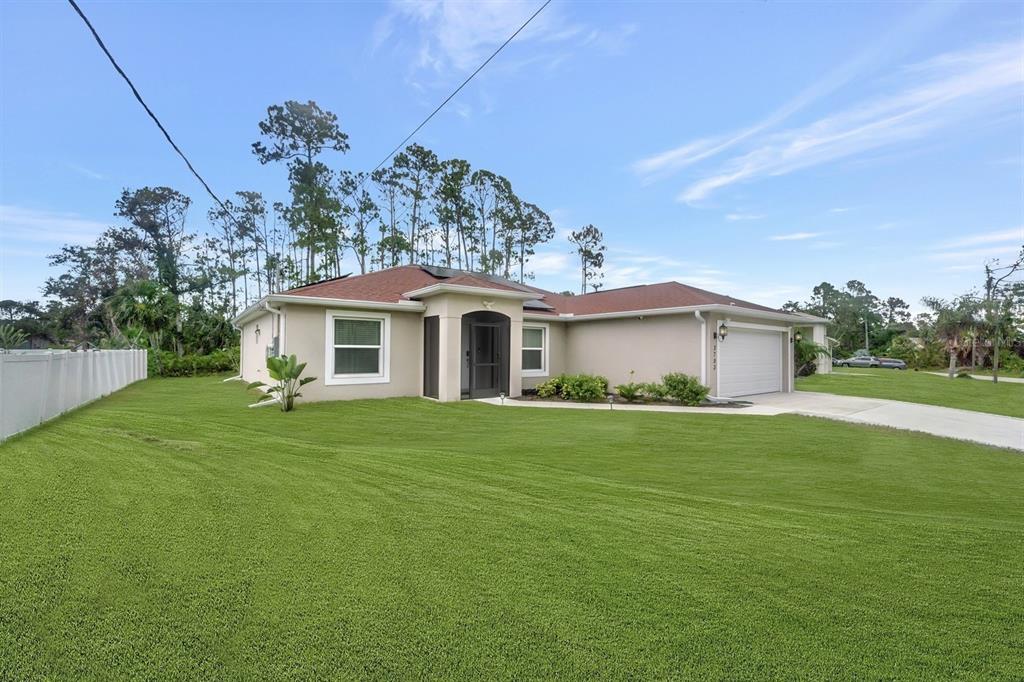 A single-story house with a tan exterior, red roof, and attached garage sits on a lawn — 3793 CIRCLEVILLE STREET, NORTH PORT, FL