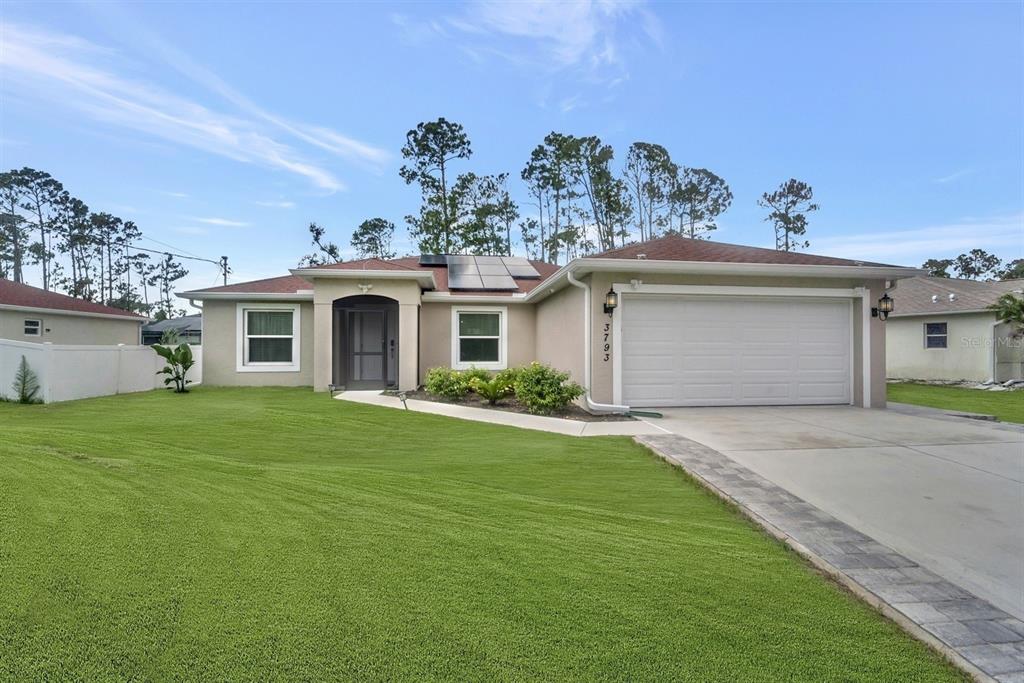 A single-story house with a white garage door, solar panels, and a green lawn — 3793 CIRCLEVILLE STREET, NORTH PORT, FL