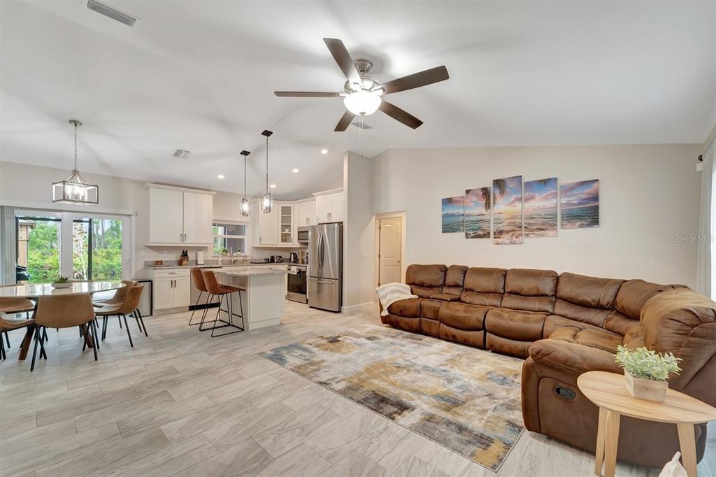 An open-concept living room and kitchen featuring a brown sectional, tile floors, and stainless appliances — 3793 CIRCLEVILLE STREET, NORTH PORT, FL