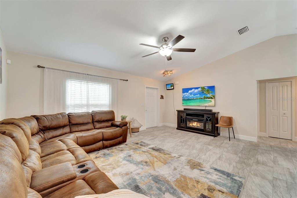 A living room features a brown sectional sofa, a fireplace console, and a ceiling fan — 3793 CIRCLEVILLE STREET, NORTH PORT, FL