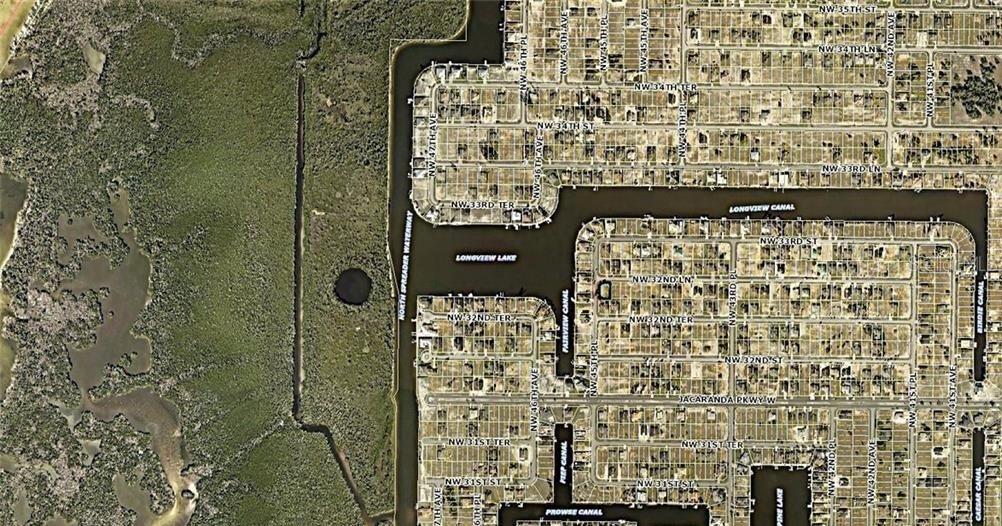 This aerial map shows a residential neighborhood bordering a canal, lake, and undeveloped wooded land — 4430 NW 32ND LANE, CAPE CORAL, FL