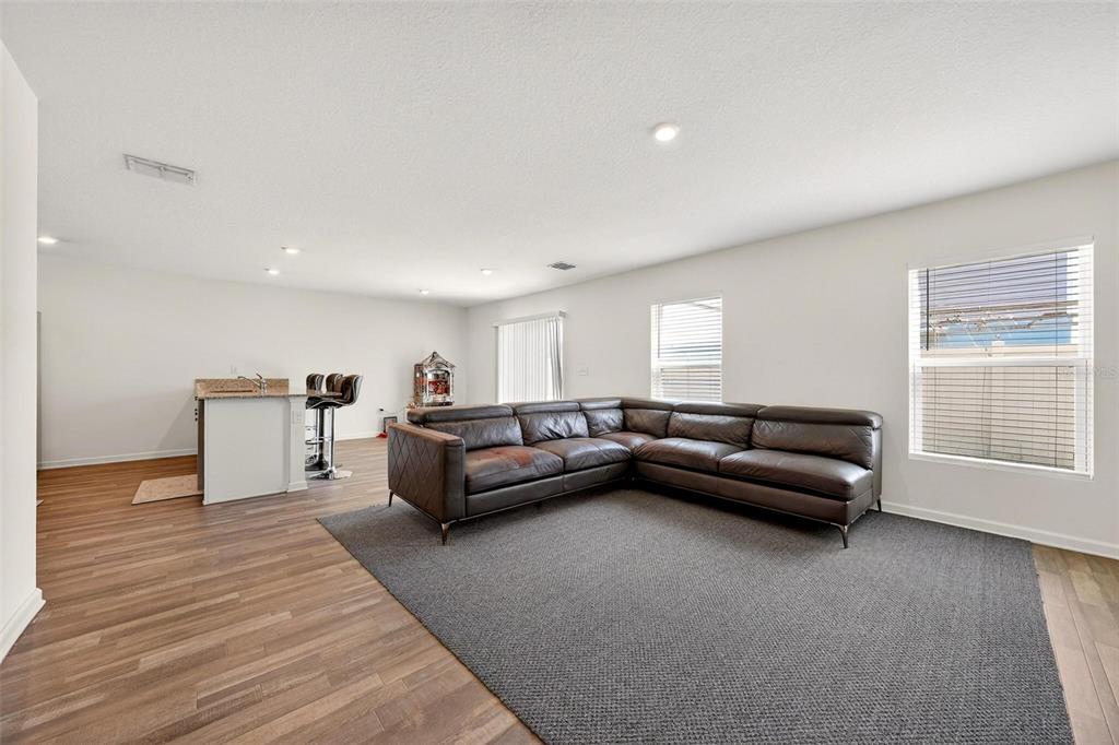 A living room features a large brown sectional sofa on a gray rug near a kitchen — 1665 MINNESOTA ROAD, SUMTERVILLE, FL
