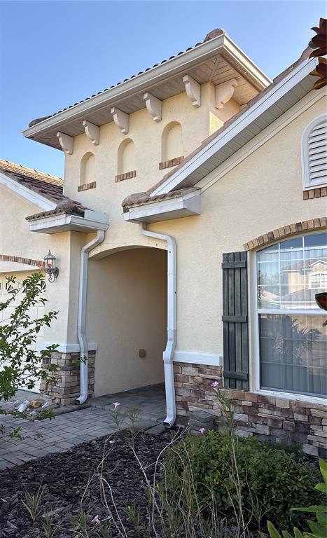 The exterior of a house features a stucco facade, stone accents, and a covered entryway — 10864 CORY LAKE DRIVE, TAMPA, FL