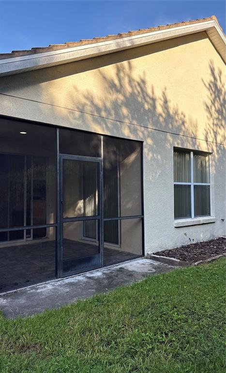 The exterior of a house features a screened-in patio and a window with vertical blinds — 10864 CORY LAKE DRIVE, TAMPA, FL