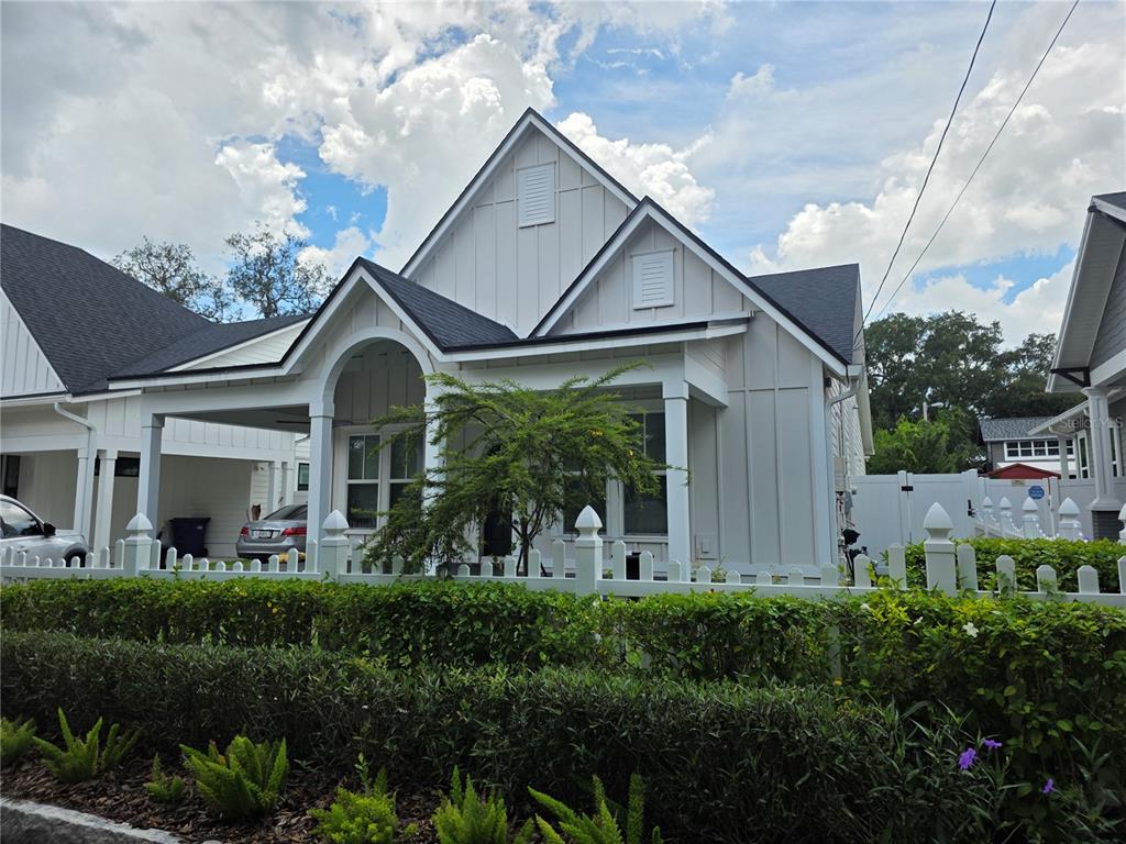 A white farmhouse-style house with board and batten siding sits behind a white picket fence — 3016 N MASSACHUSETTS AVENUE, TAMPA, FL