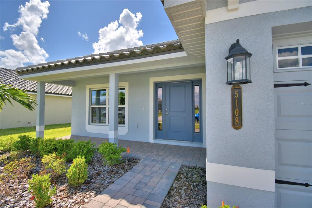 A light blue single-story house with a tiled roof sits behind a large green lawn — 4705 GRANDVIEW GLEN DRIVE, AUBURNDALE, FL