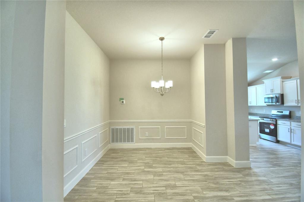 An open-concept dining area and living space feature light wood-look tile flooring and white cabinetry — 4705 GRANDVIEW GLEN DRIVE, AUBURNDALE, FL
