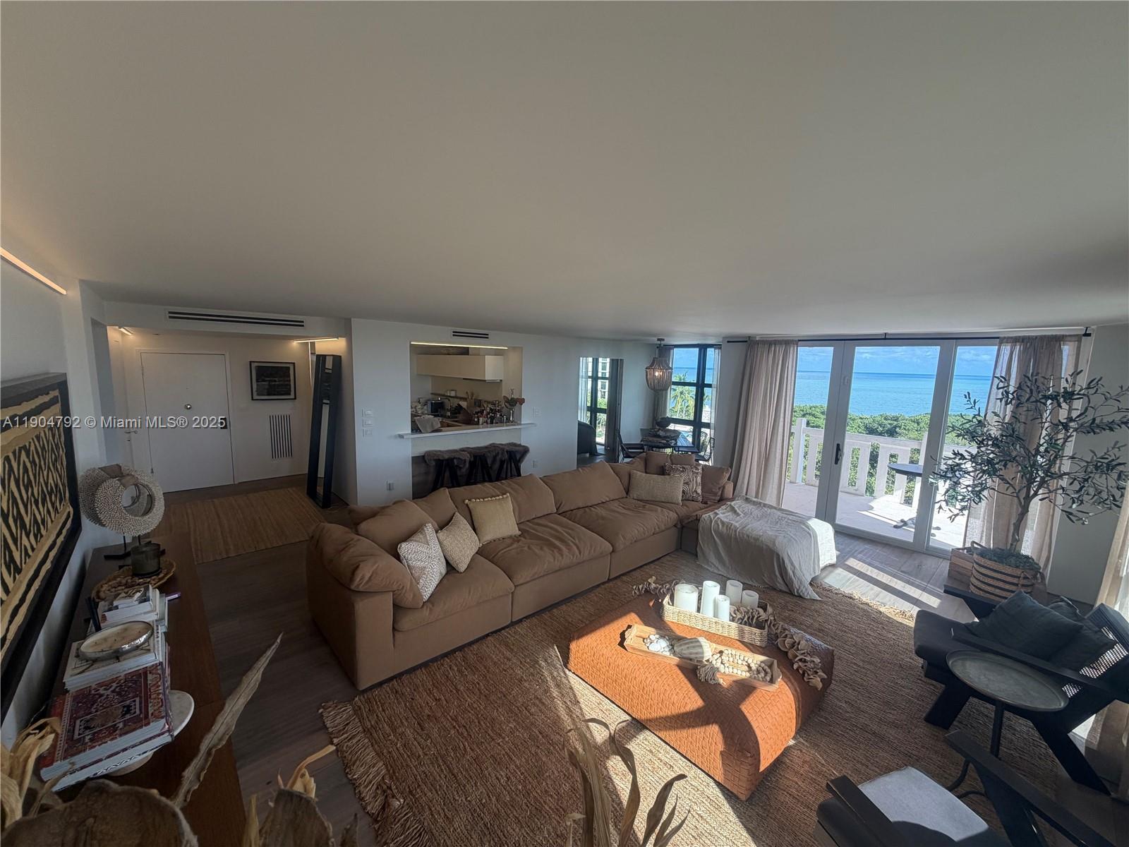 A spacious living room features a large brown sectional, jute rug, and ocean views — 1121 Crandon Blvd # D608, Key Biscayne FL 33149, KEY BISCAYNE, FL