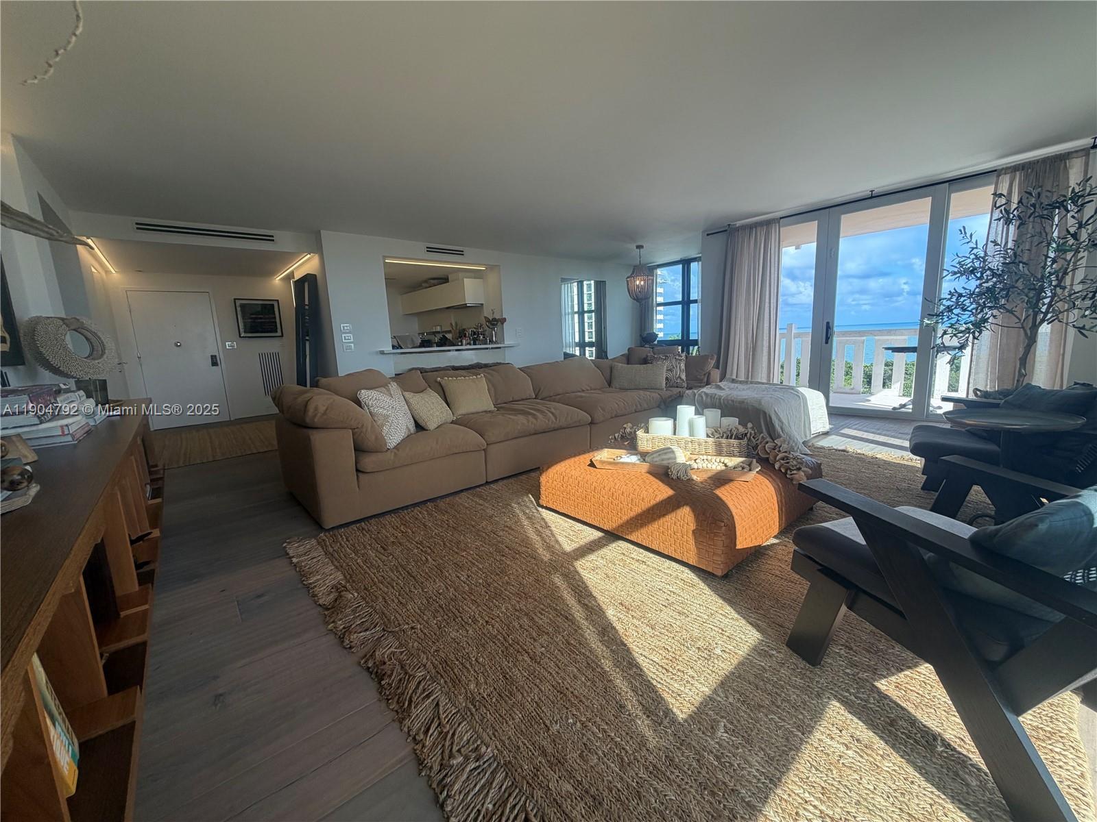 A living room features a large brown sectional, a textured rug, and a balcony view — 1121 Crandon Blvd # D608, Key Biscayne FL 33149, KEY BISCAYNE, FL