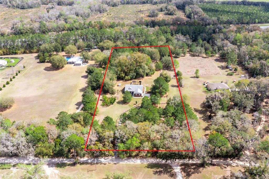 A fenced, grassy pasture with scattered trees and a small covered structure on the right — 22317 NW 188TH STREET, HIGH SPRINGS, FL
