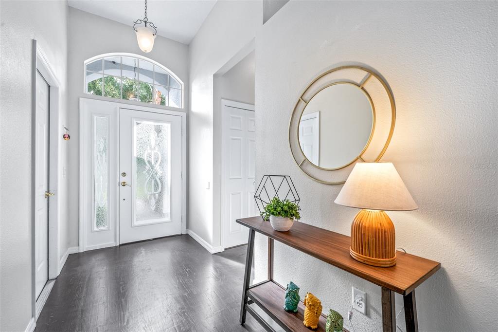An entryway features dark wood flooring, a white front door, and a console table — 7805 BRISBANE COURT, NEW PORT RICHEY, FL
