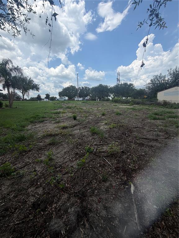 A vacant, grassy lot with scattered debris under a blue sky with clouds — 0000 SE HIGHWAY 42, SUMMERFIELD, FL