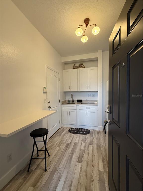 A small kitchen area features white cabinets, a breakfast bar, and light wood-look flooring — 12245 PRAIRIE PLANTATION WAY, ORLANDO, FL