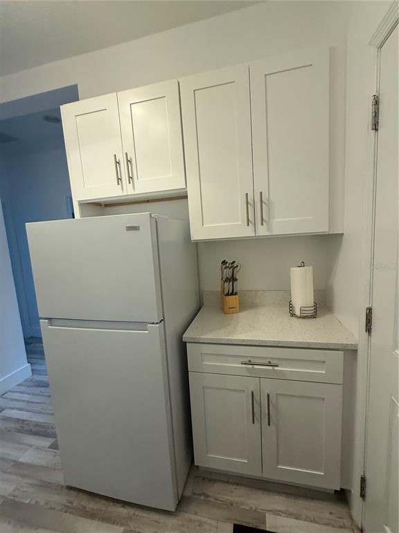 A white refrigerator stands next to white kitchen cabinets and a stone countertop — 12245 PRAIRIE PLANTATION WAY, ORLANDO, FL