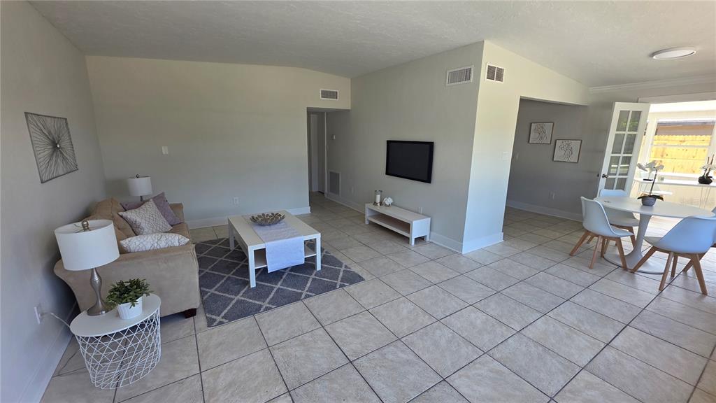 A living room and dining area feature light tile flooring, neutral walls, and modern furniture — 3167 IRVING STREET, SARASOTA, FL