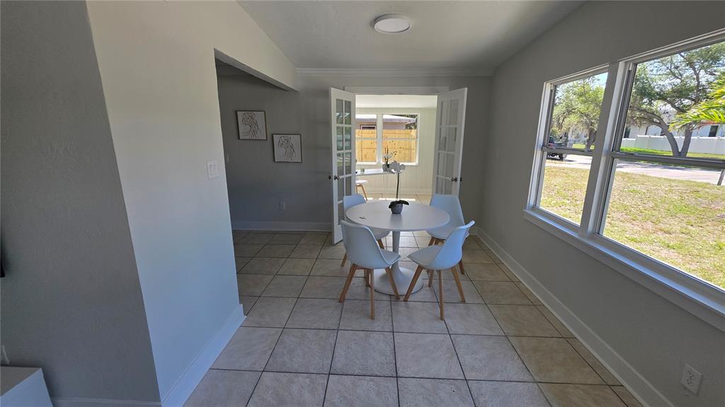 A dining area features a white pedestal table, four chairs, tile flooring, and French doors — 3167 IRVING STREET, SARASOTA, FL